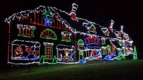 A festive house decorated with colorful Christmas lights, featuring holiday scenes and bright decorations.