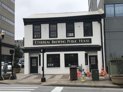 A white building with a sign reading "Ethereal Brewing Public House," located on a city street.