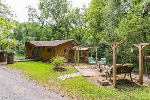 A cozy, rustic cabin surrounded by trees, with a wooden deck and outdoor seating area.