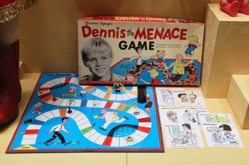 A vintage "Dennis the Menace" board game with colorful game board and cards, featuring the character and playful illustrations.