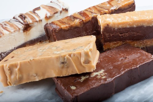 A variety of fudge bars in different flavors, including chocolate and caramel, arranged on a marble surface.