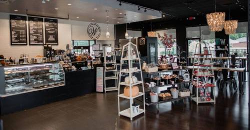 Cozy café interior featuring a display case, menu board, and shelves with baked goods and decor items.