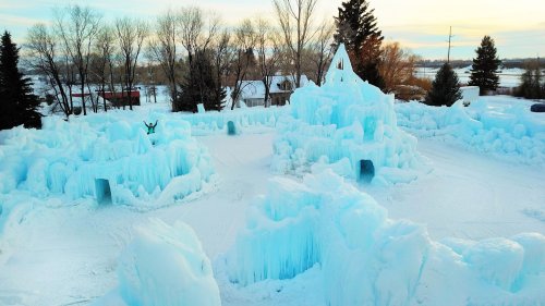 Aerial view of a large ice sculpture park with towering icy formations and a person standing among them.