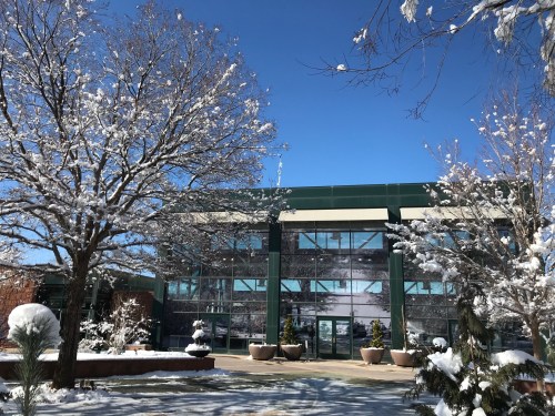 A modern building surrounded by snow-covered trees under a clear blue sky.
