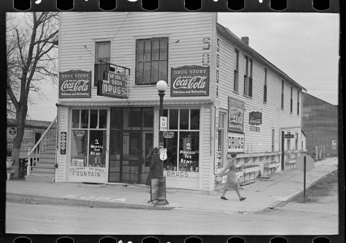 A vintage drugstore with Coca-Cola signage, featuring a fountain and two "For Rent" signs outside.