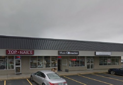 A storefront with "Top Nails" and "Music Connection" signs, featuring a gray car parked in front. Overcast sky above.