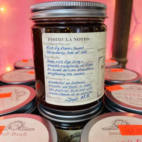 A jar of small-batch jam with a label describing rich fig and sweet strawberry flavors, recommended for pastries.