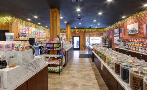 A colorful candy shop interior with jars of sweets, snacks, and festive decorations along the walls.
