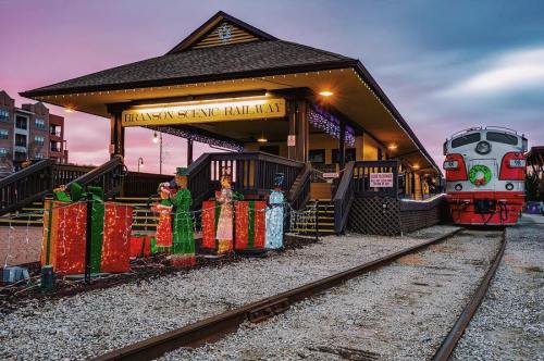 Branson Scenic Railway station at sunset, decorated with colorful holiday lights and presents along the tracks.