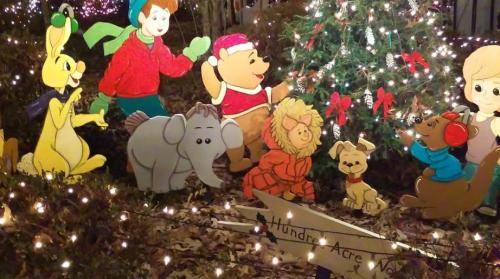 Colorful cutouts of cartoon characters, including a bear and a rabbit, gathered around a decorated Christmas tree.