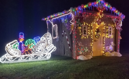 A brightly lit holiday-themed house with colorful decorations and a glowing sleigh filled with festive treats.