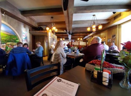 A busy restaurant interior with diners at tables, warm lighting, and a mural on the wall.