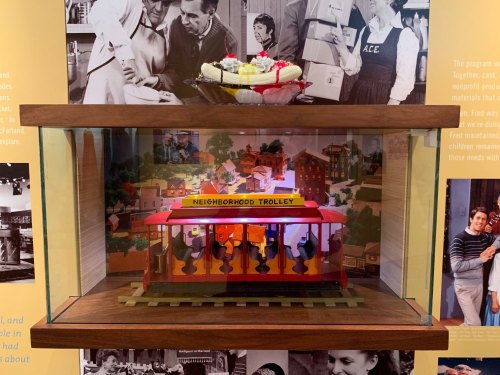 A display case featuring a colorful model trolley labeled "Neighborhood Trolley" with a backdrop of historical photos.
