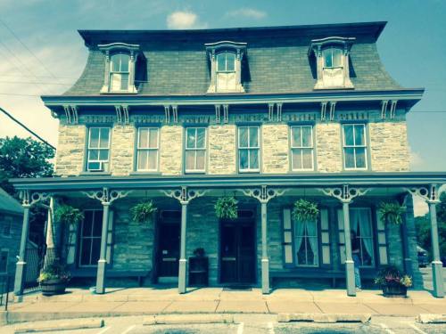 Historic stone building with a decorative roof, large windows, and hanging plants, set against a clear blue sky.