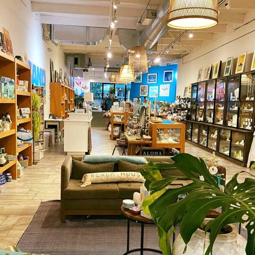 A bright, inviting store interior with shelves of decor, art, and furniture, featuring a cozy seating area.