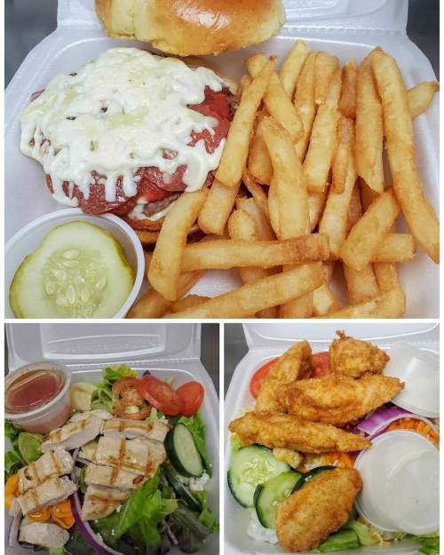 A takeout meal featuring a sandwich with sauce, fries, a salad with grilled chicken, and fried chicken strips.