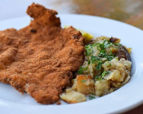 A plate featuring a crispy fried fillet alongside a serving of seasoned potato and herb mixture.
