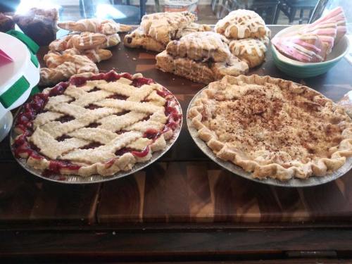 Two freshly baked pies on a wooden table: one with a lattice crust filled with red fruit, the other topped with cinnamon.