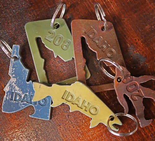 A collection of metal keychains shaped like Idaho, featuring the state outline and the number 208.