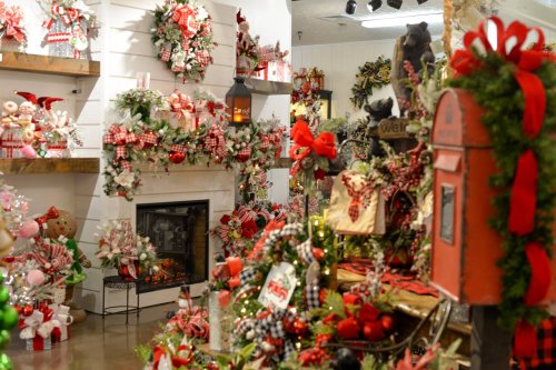 A festive store display filled with Christmas decorations, wreaths, and holiday-themed items in red and green.