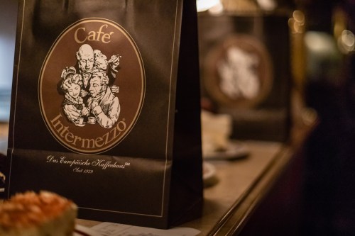 A close-up of a Café Intermezzo bag featuring a vintage logo and warm, ambient lighting in a café setting.