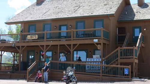 A wooden building with a sign reading "1875," featuring a man and two children outside, and a motorcycle nearby.