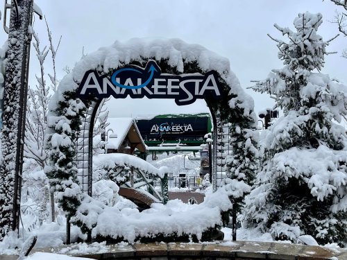Snow-covered entrance archway to Anakeesta, surrounded by trees blanketed in fresh snow.