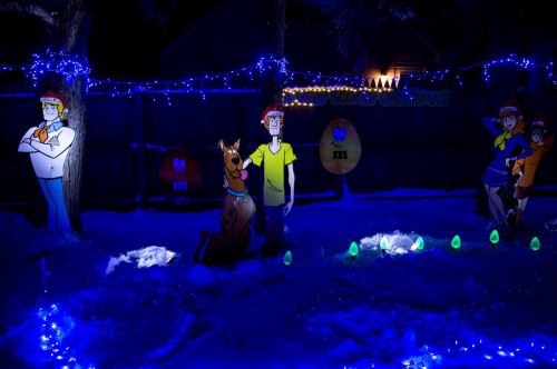 A snowy yard decorated with blue lights featuring Scooby-Doo characters and colorful cutouts.