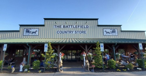 Exterior of The Battlefield Country Store, featuring a green roof, wooden beams, and decorative landscaping.