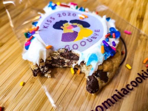A partially eaten cookie with colorful frosting, sprinkles, and a "Kiss 2020 Goodbye" logo on top.