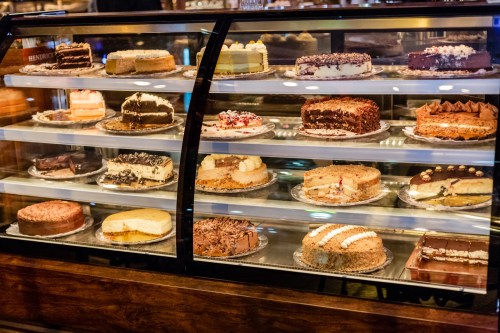 A display case filled with various cakes, including chocolate, cheesecake, and layered desserts, all beautifully arranged.