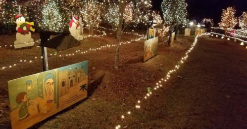 A festive pathway lined with lights and holiday decorations, featuring painted scenes and snowman figures.