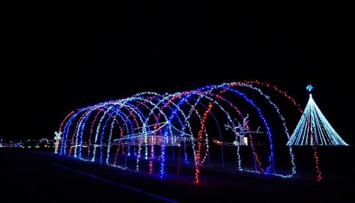 Colorful holiday lights form arches and a tree against a dark night sky, creating a festive atmosphere.