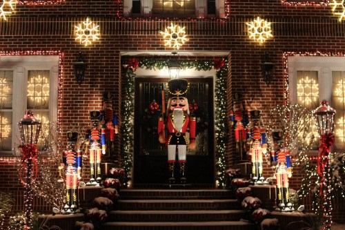 A festive house decorated with lights, snowflakes, and nutcracker figures on the steps, creating a cheerful holiday scene.