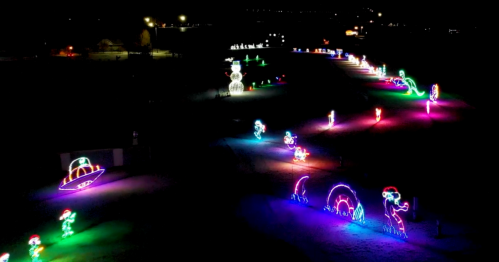 Colorful holiday light displays featuring various characters and shapes in a dark park setting.