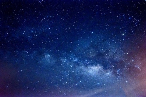 A starry night sky filled with countless stars and a faint Milky Way band across the dark blue backdrop.