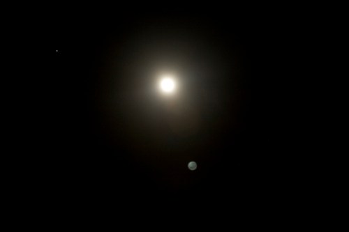 A bright full moon surrounded by a dark sky, with a small star visible in the upper left corner.