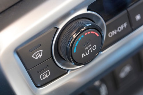 Close-up of a car's climate control dial with "AUTO" setting and adjacent buttons for defrost and power.