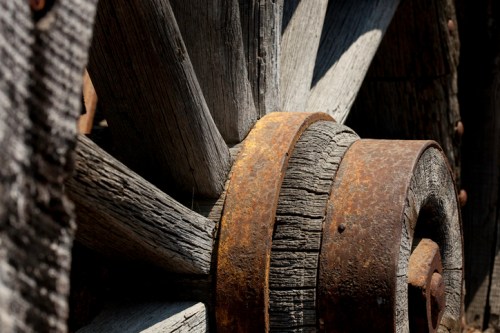 Close-up of a weathered wooden wheel with rusty metal bands, showcasing textures and details of aged materials.