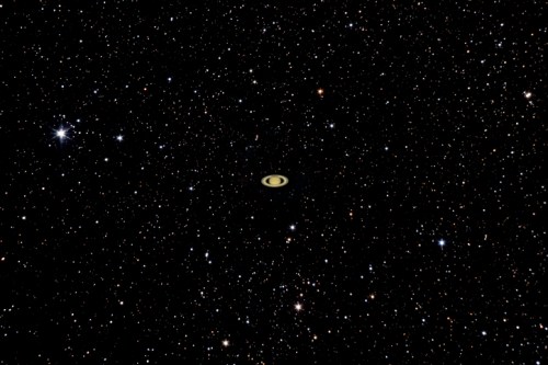 A distant galaxy surrounded by countless stars, featuring a prominent ringed structure at its center.