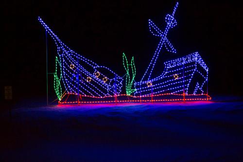 Colorful holiday lights depict a shipwreck scene with a ship, anchor, and seaweed against a dark background.