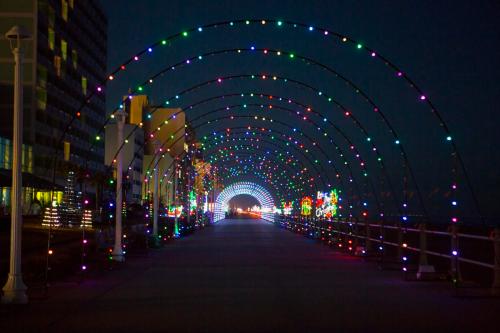 A brightly lit archway of colorful lights along a walkway at night, creating a festive atmosphere.