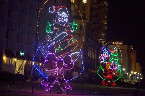 Colorful holiday lights display featuring Santa and Christmas decorations along a beach at night.