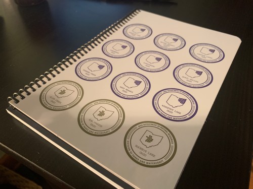 A spiral notebook page featuring various circular stamps or seals in different colors and designs.
