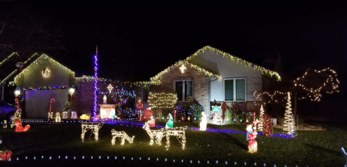 A festive house decorated with colorful lights and holiday decorations, including figures and ornaments, at night.