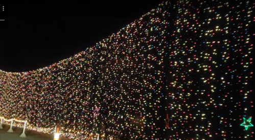 A vibrant display of colorful holiday lights covering a curved wall at night.