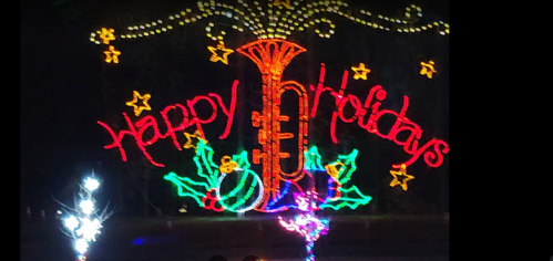 Colorful holiday lights display featuring a trumpet and the text "Happy Holidays" surrounded by stars and festive decorations.