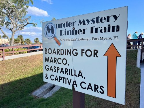 Sign for the Murder Mystery Dinner Train in Fort Myers, FL, indicating boarding for Marco, Gasparilla, and Captiva cars.