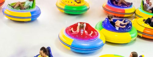 Colorful bumper cars in motion, with children enjoying a fun ride at an amusement center.