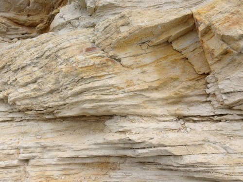 Close-up of layered sandstone rock formation with light beige and yellow hues.
